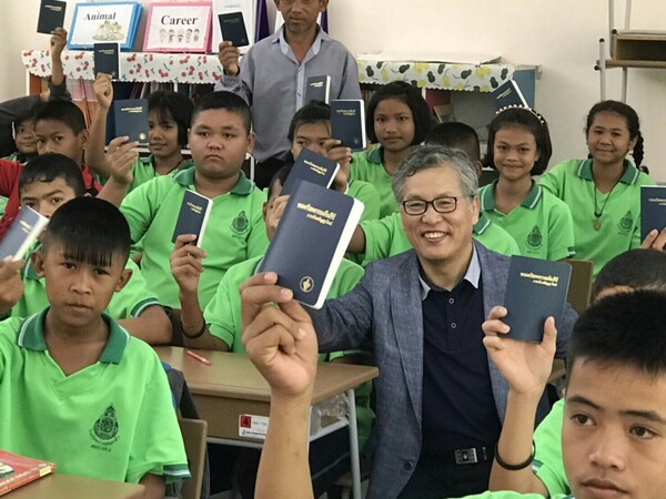 태국현지 학교의 학생들에게 성경책을 나눠주고 환하게 웃고 있는 변도우 장로