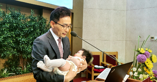 김중식 포항중앙침례교회 목사가 지난 24일 주일 대예배 때 신생아를 안고 축복기도를 하고 있다.