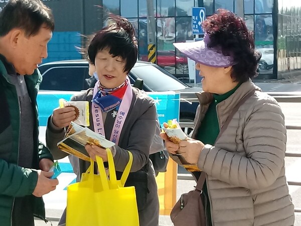 시민을 향해 전도 용품과 전도지를 나눠주며 설명하고 있다. @출처=웨슬리 전도대