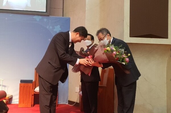 신임 노회장 김정태 목사가 권동화 목사와 지성범 목사에게 꽃다발을 전하고 있다