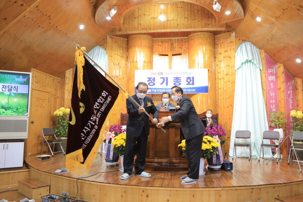 김병완 목사가 신임 대표회장 홍석용 목사에게 연합회기를 건내고 있다.