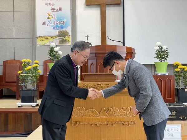 유명권 감독이 원산도교회 이정열 목사에게 지원금을 전달하고 있다.