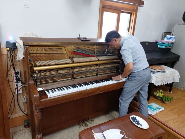 단장 이동석 집사가 시골교회에 방문해 무료로 피아노를 조율하고 있다. @출처=노래하는 순례자