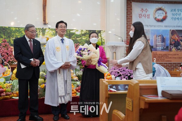 (사진 왼쪽부터) 1대 담임목사 김영교 목사와 2대 담임목사 김용학 목사가 성도들로부터 꽃다발과 선물을 받고 있는 모습