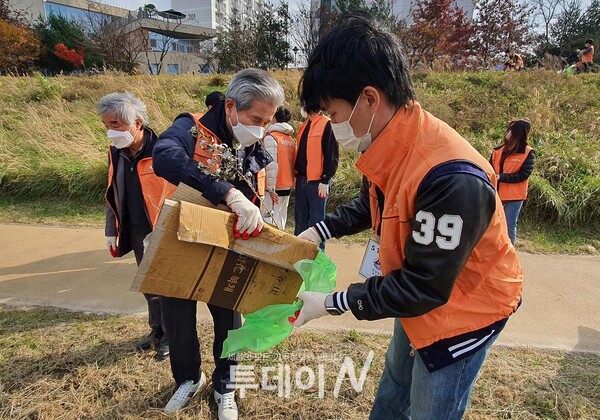 권혁대 총장이 주운 쓰레기를 학생들과 함께 비닐 주머니에 담고 있다.