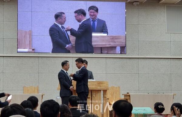 노회장로회가 임직한 장로에게 뺏지를 달아주고 있다.